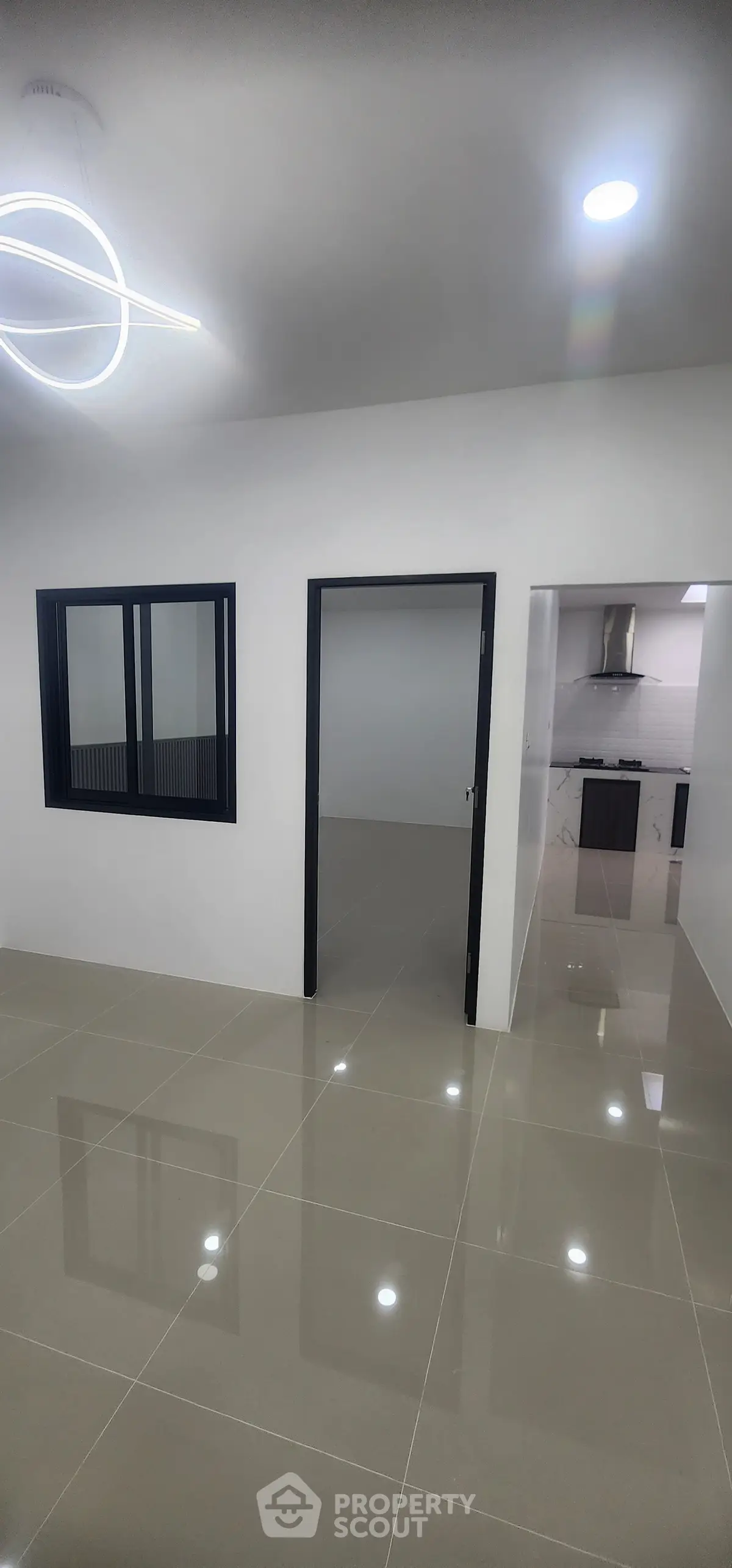 Modern interior with sleek kitchen and glossy tiled floors, featuring contemporary lighting.