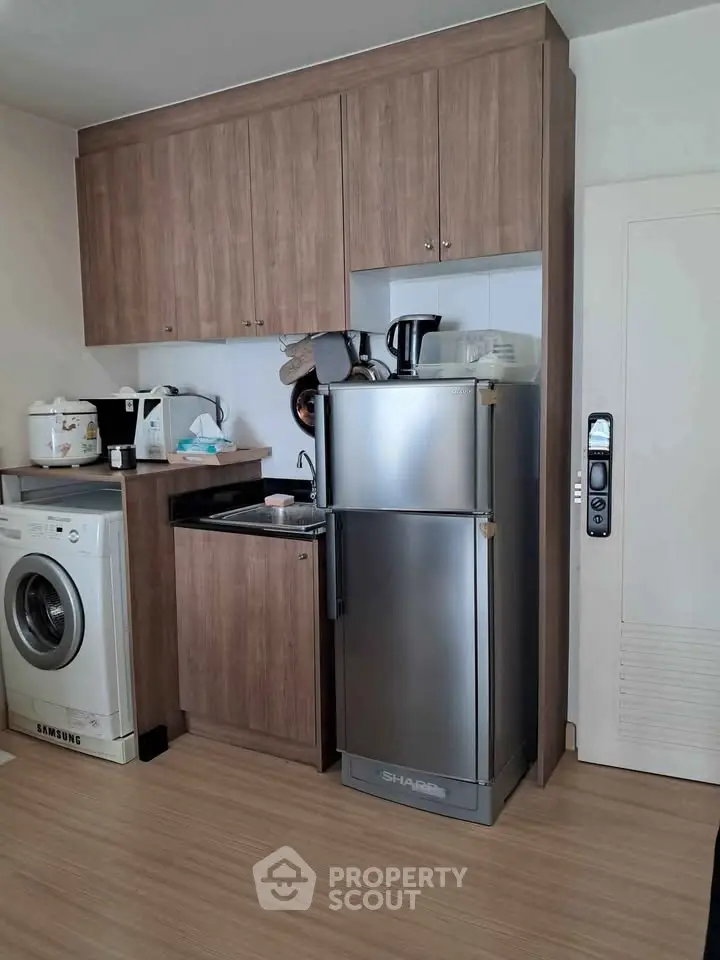Compact kitchen with wooden cabinets, washing machine, and stainless steel fridge