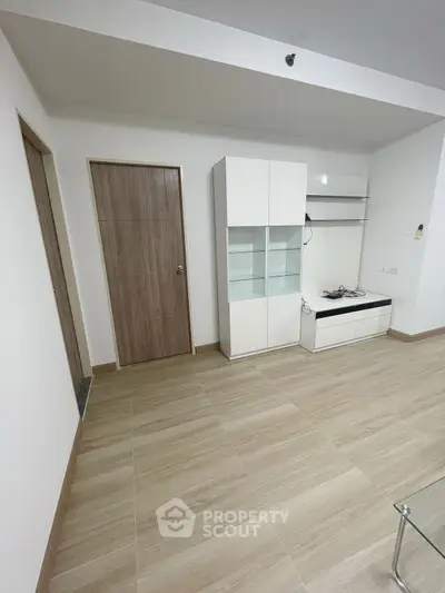 Modern minimalist living room with sleek white cabinets and wooden flooring.