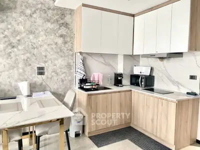 Modern kitchen with sleek cabinetry and dining area, featuring marble countertops and stylish decor.