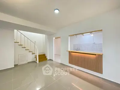 Modern open-plan living area with sleek staircase and stylish kitchen counter