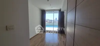 Bright room with wooden flooring and large window offering city view, ideal for versatile use.