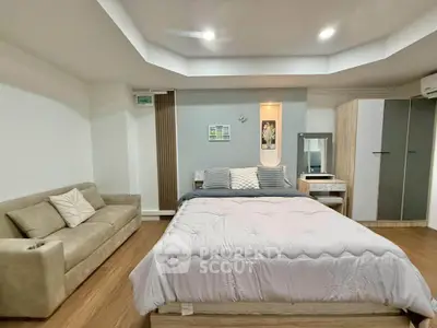 Spacious bedroom with modern decor and cozy seating area, perfect for relaxation.