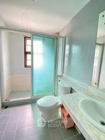 Modern bathroom with glass shower and sleek fixtures in bright natural light.