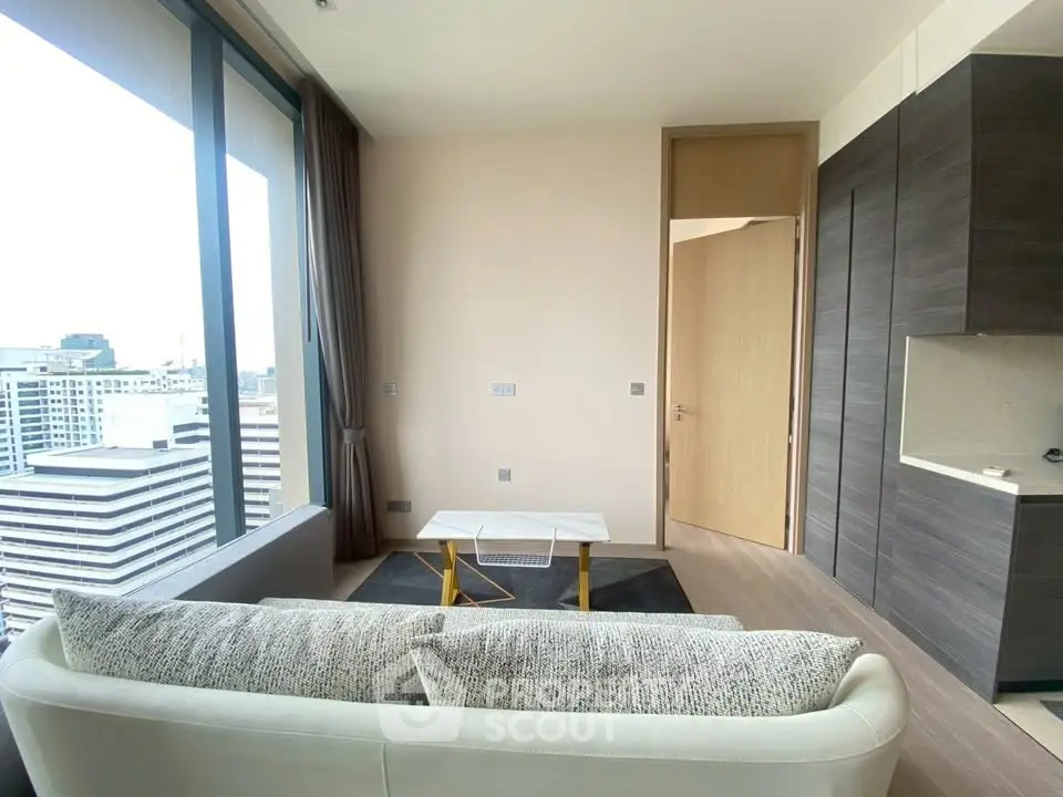 Modern living room with city view, featuring sleek furniture and large windows.