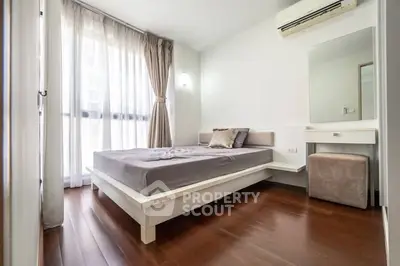 Modern bedroom with wooden flooring and large window for natural light.