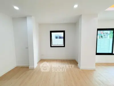 Spacious modern interior with wooden flooring and large windows, perfect for natural light.