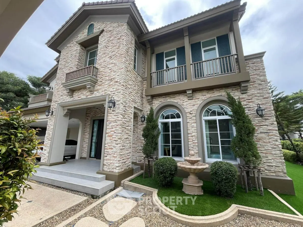 Stunning two-story stone facade house with elegant arched windows and lush landscaping.