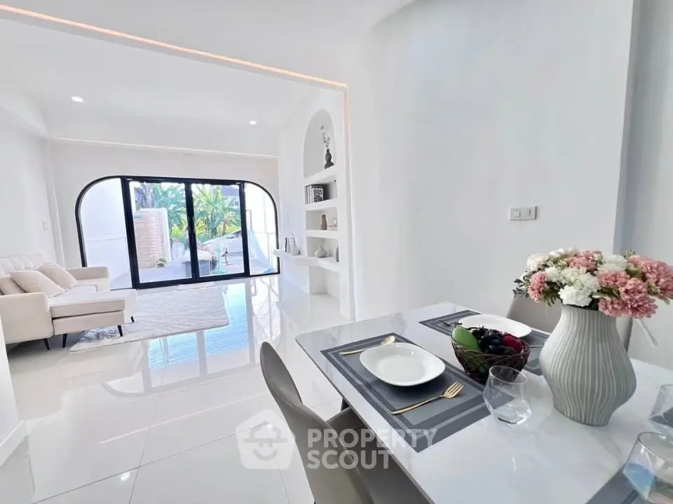 Luxurious open-plan living room with elegant dining area and large windows offering garden views.
