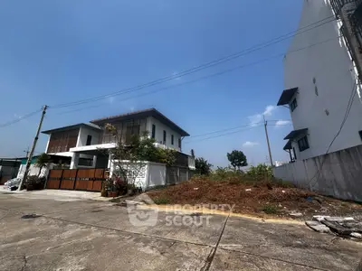 Charming suburban house with spacious driveway and lush greenery under a clear blue sky.