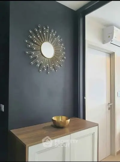 Modern interior with stylish sunburst mirror and sleek wooden cabinet, showcasing contemporary design.