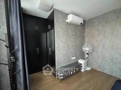 Modern bedroom with sleek black wardrobe and air conditioning unit