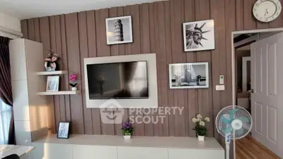 Modern living room with stylish decor and wall-mounted TV, featuring elegant wood paneling and framed art.