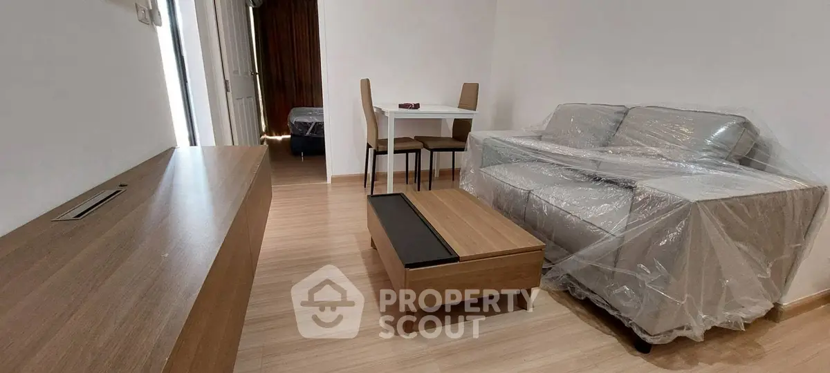 Cozy living room with modern furniture and a glimpse of the bedroom, perfect for urban living.