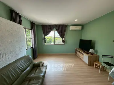 Spacious living room with green walls, leather sofa, and large window view.