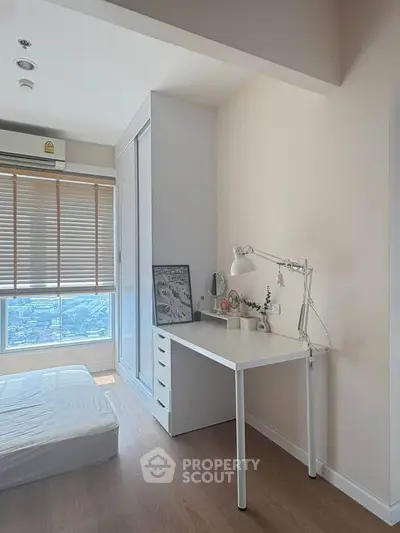 Bright bedroom with study area and city view, featuring modern decor and natural light.