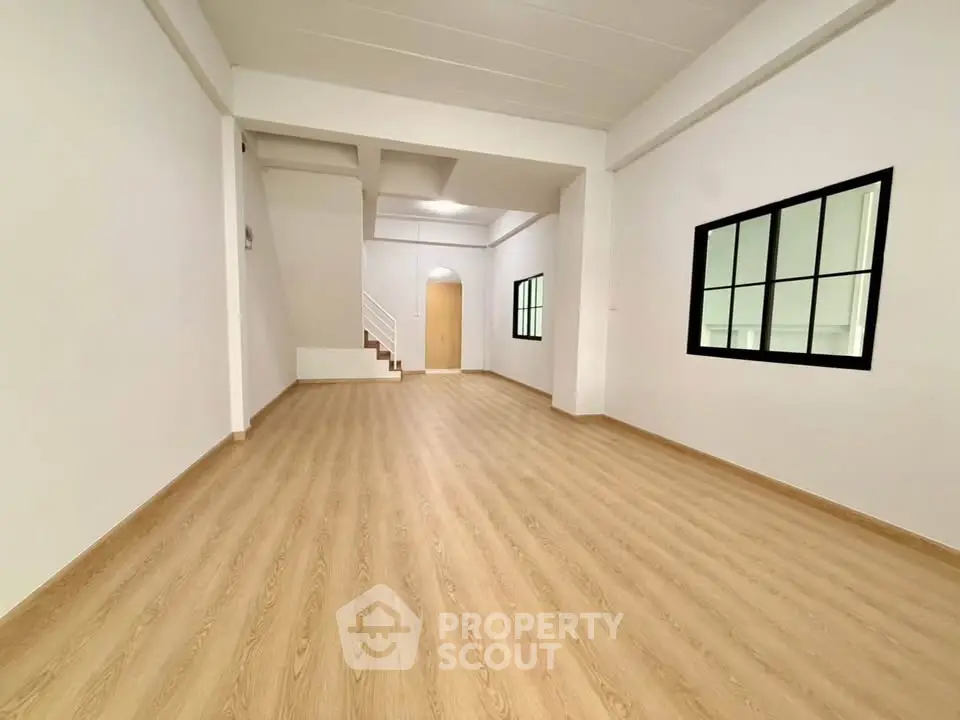Spacious open-plan living area with modern wood flooring and large windows.