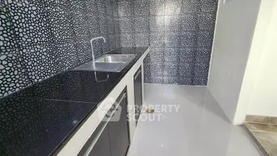 Modern kitchen with sleek black countertops and unique tiled backsplash