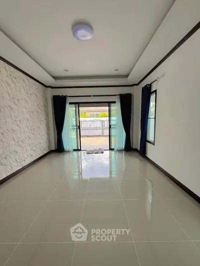 Spacious empty living room with large windows and modern tile flooring.