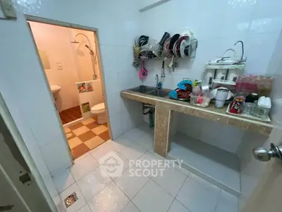 Compact kitchen with open shelving and adjacent bathroom in a cozy apartment.