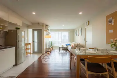 Spacious open-plan living room with modern kitchen and dining area, featuring stylish decor and ample natural light.