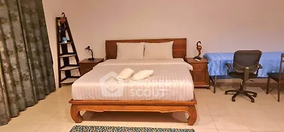 Spacious bedroom with elegant wooden bed and cozy study area, perfect for relaxation and productivity.