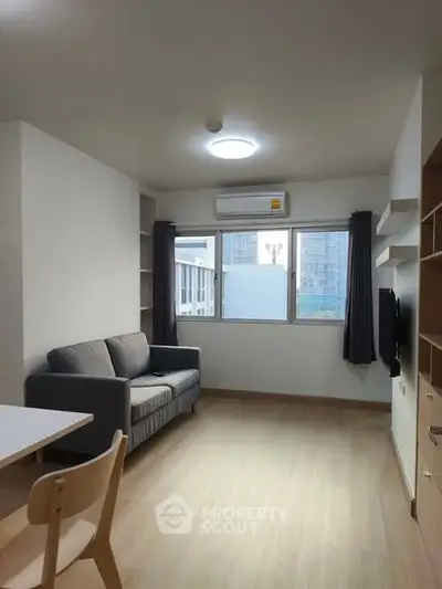 Modern living room with natural light, featuring a cozy sofa and sleek wooden flooring.
