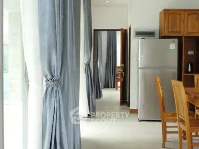 Spacious kitchen with modern appliances and elegant curtains in a bright, airy setting.