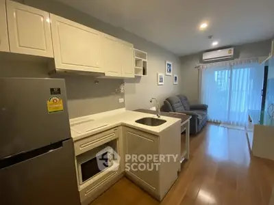Modern open-layout kitchen and living room with sleek appliances and cozy seating area.