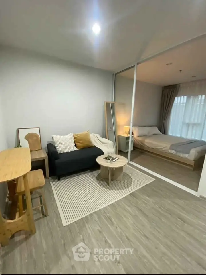 Modern studio apartment with cozy living area and bedroom separated by glass partition.