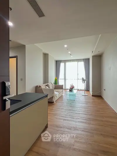 Spacious modern living room with wooden flooring and large windows offering natural light.