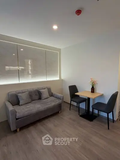 Modern living room with cozy gray sofa and dining area, featuring elegant decor and wooden flooring.