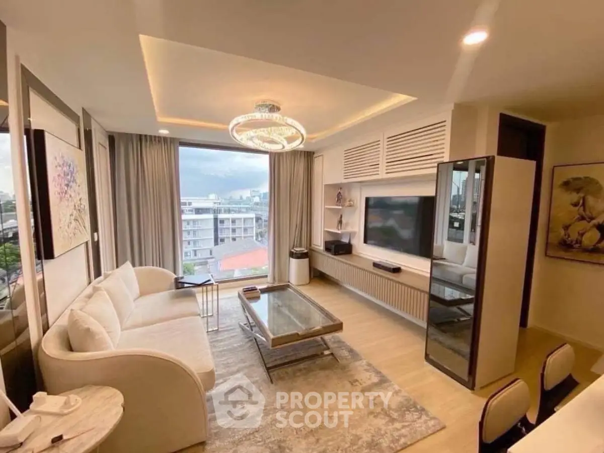 Modern living room with elegant decor and city view, featuring a cozy sofa and stylish chandelier.