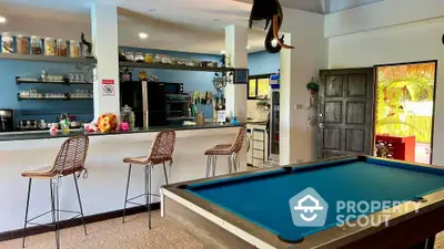 Spacious open-plan kitchen with bar seating and pool table, perfect for entertaining.