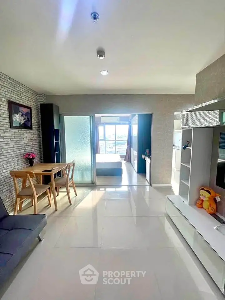 Bright modern living room with open layout and stylish decor, leading to a cozy bedroom with natural light.