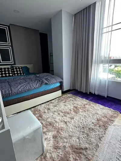 Spacious bedroom with large window and plush carpet in modern apartment