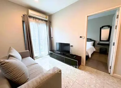 Modern living room with cozy sofa and TV, leading to a stylish bedroom with elegant decor.