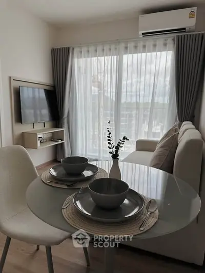 Modern living room with dining area and large window in a stylish apartment.