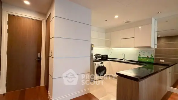 Modern kitchen with sleek cabinetry and built-in washing machine in a stylish apartment.