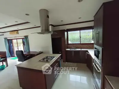 Spacious modern kitchen with island and gas stove, ample natural light and sleek cabinetry.