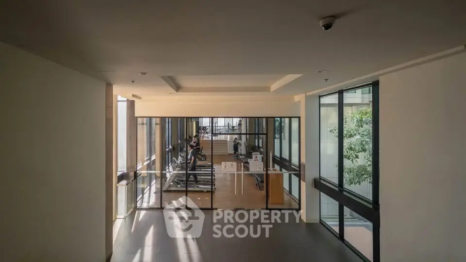 Modern gym with large windows and exercise equipment in a residential building.