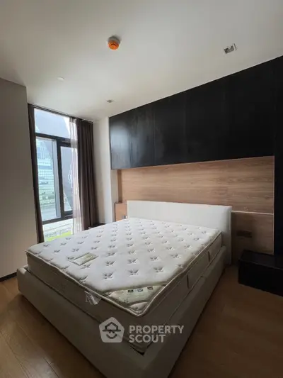Spacious bedroom with large window and modern design in a luxury apartment.