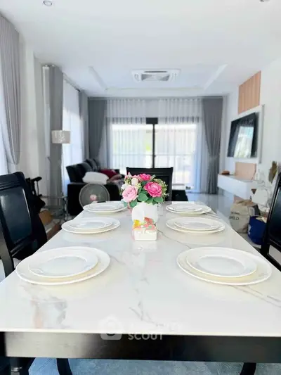 Elegant dining area with marble table and floral centerpiece in modern living room.