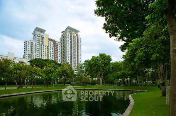 Stunning view of modern high-rise buildings surrounded by lush greenery and a serene pond.