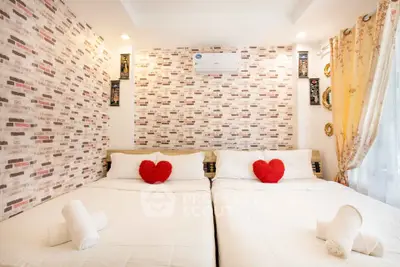 Charming bedroom with twin beds, heart-shaped pillows, and stylish brick accent wall.