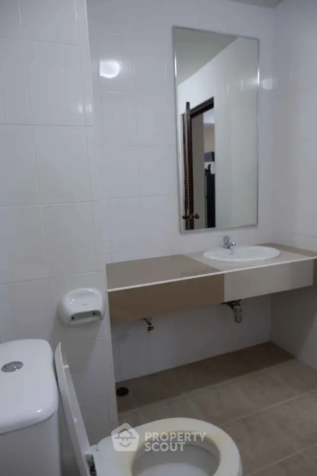 Modern bathroom with sleek design and neutral tones, featuring a large mirror and contemporary fixtures.
