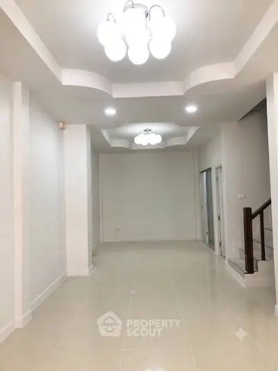Spacious modern interior with elegant lighting and staircase, perfect for versatile living space.