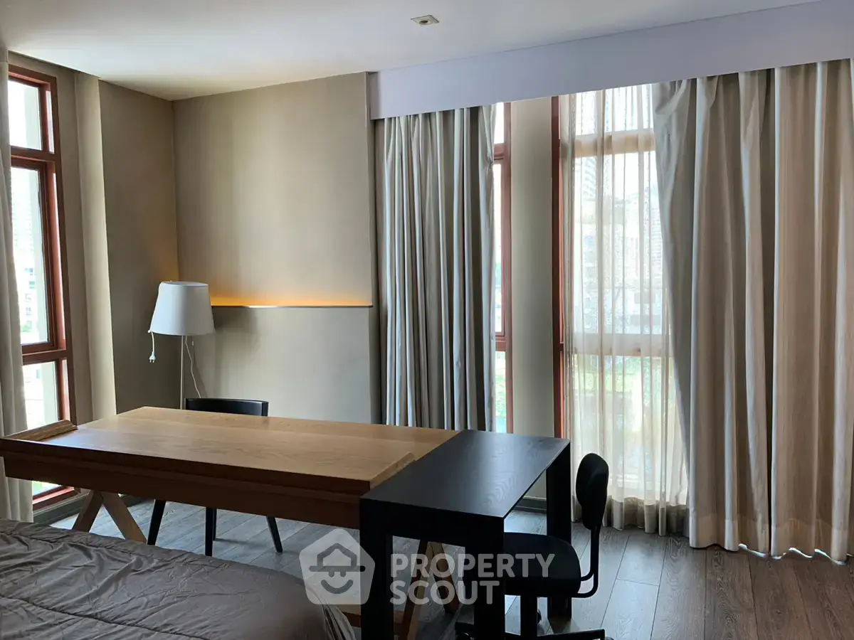Modern bedroom with study area featuring large windows and elegant curtains