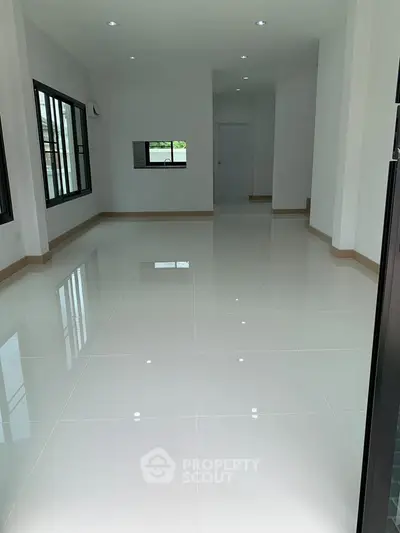 Spacious modern living room with glossy white tiles and large windows