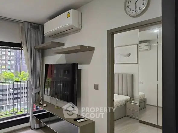 Modern living room with wall-mounted TV and view into stylish bedroom.